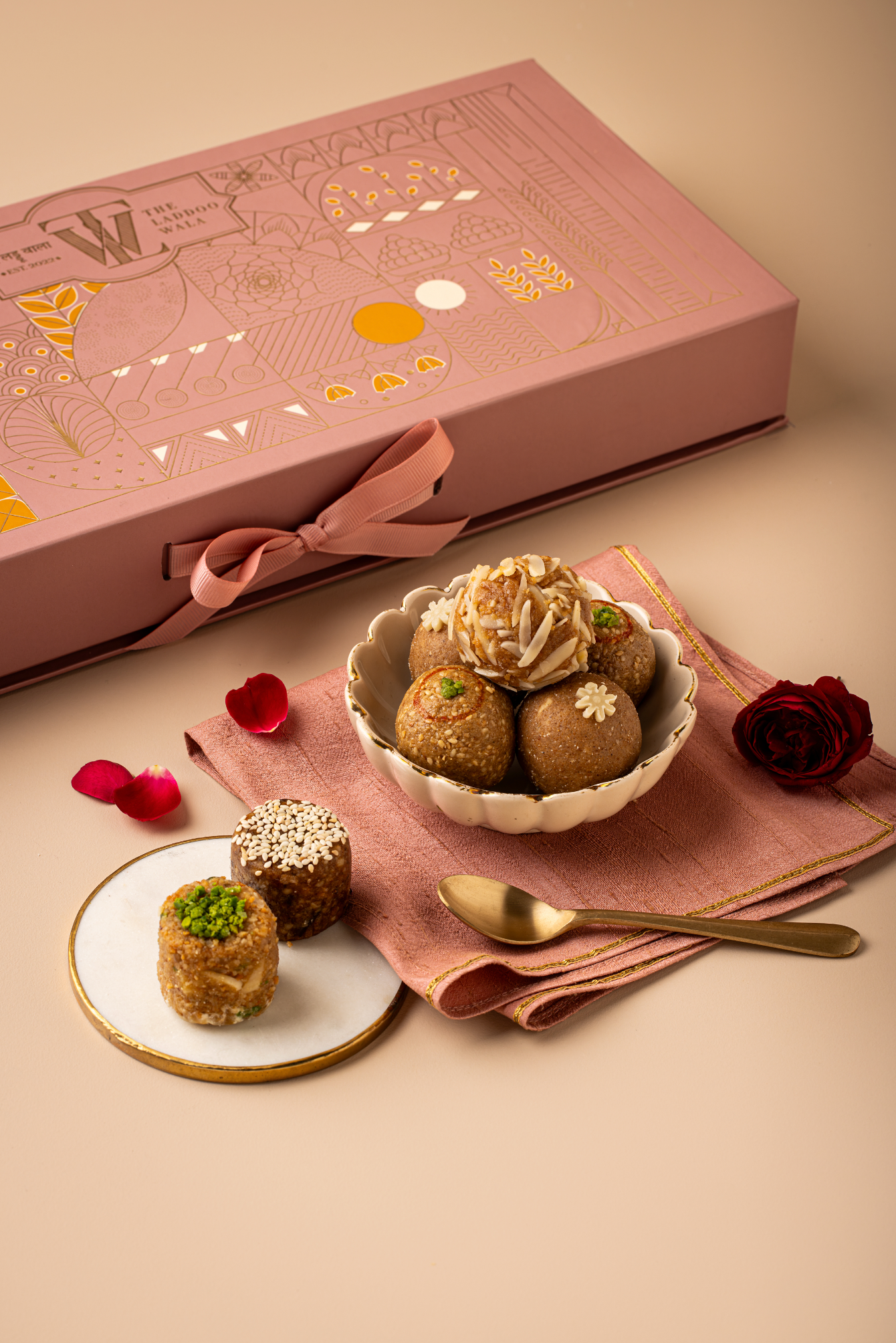 TLW Jodha Box inspired by Rajput princess Jodha Bai, featuring an assorted royal laddoo collection including Til Gur, Atta Panjiri, TLW Nuts, Dates & Walnuts, and Mewari Churma laddoos in an elegant premium gift box.